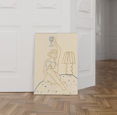 a painting is sitting on the floor in front of a wall with a lamp next to it