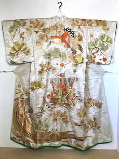 A stunning Uchikake wedding Kimono with extensive embroidered Crane, Flying Turtle, Pine branches & Treasure Ship.   This Japanese long sleeved dress is heavy weight with embroidery.  Please read full description. Fits a USA size S-M. *$100 Express Shipping has been included in price & is Non-refundable.  Please review photos and description carefully before ordering. Thank you! MATERIAL:  Heavily embroidered silk  fabric.  Interior synthetic with padded bottom. COLOR:  Ivory white with metallic silver bright orange green yellow & embroidery in metallic gold. DETAILS:  Fabric has crane pattern tone-on-tone with silver metallic sparkles and extensive gold embroidery. CONDITION:  Used, vintage.  Light stain on front collar at waist-line & on back / some blue horizontal blue dye lines at lap Flying Turtle, Crane Flying, Ship Embroidery, Japanese Wedding Dress, Treasure Ship, Crane Pattern, Yellow Embroidery, Japanese Wedding, Wedding Kimono