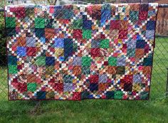 a quilt hanging on a chain link fence