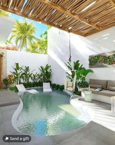 an indoor swimming pool surrounded by greenery and white furniture with a wooden roof over it