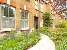 a brick building with lots of windows next to a garden