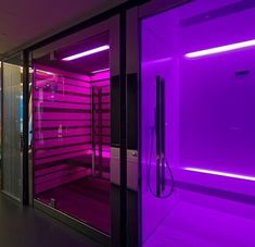 an empty room with purple lighting on the walls and glass doors that lead into it