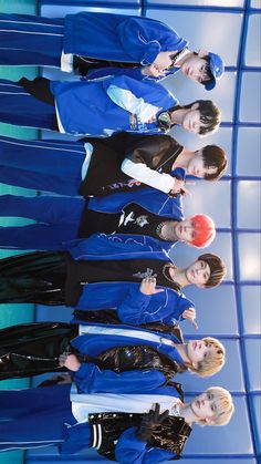 four young women in blue jackets and black pants standing next to each other with their hands on their hips