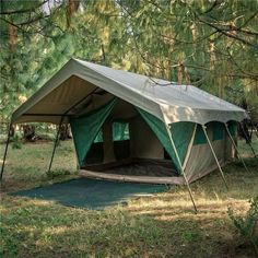 a tent set up in the middle of a field with trees and grass around it