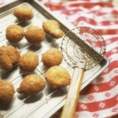 some fried food is on a metal tray with a strainer and red and white towel