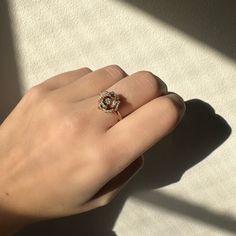 a woman's hand with a diamond ring on top of her finger, casting a shadow