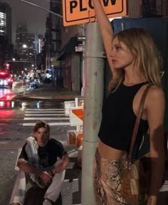 a woman standing next to a pole with a sign on it