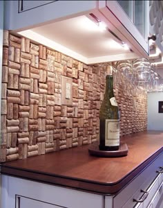 a bottle of wine sitting on top of a wooden counter next to a cork wall