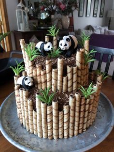 a cake made to look like bamboo sticks with pandas on top and plants in the middle