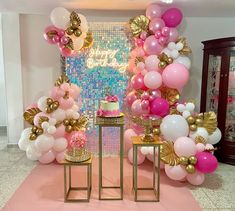 pink and gold balloons are on display at a birthday party with a cake, table and chairs