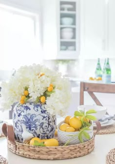 a blue and white vase sitting on top of a table filled with lemons, oranges and flowers