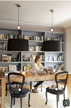 two chairs are sitting at a wooden table in front of bookshelves and shelves