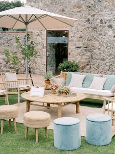 an outdoor seating area with chairs, tables and umbrellas on the grass in front of a stone building