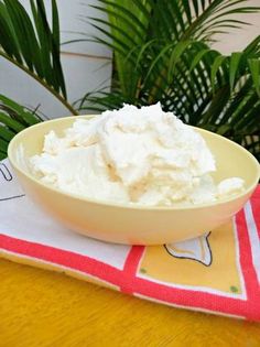 a bowl filled with whipped cream sitting on top of a table next to a potted plant