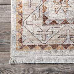 an area rug on a wooden floor with a white and orange design in the middle