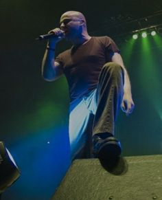 a male in a brown shirt is on stage with his legs up and one leg raised