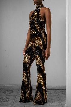 Get glam in our Licorice Swirl Sequin Halter Flare Pants Jumpsuit. This piece has an all-over two-tone black & gold sequin swirl motif design. The fabric is stretchy to flatter your curves and has a hidden zipper for easy wearing. Perfect for special events such as a birthday, black tie events, date nights, and much more. Details Jumpsuit: Stretch Shell Fabric Content: Nylon/SpandexLining Content: Polyester/SpandexCare Instruction: Hand Wash or Dry clean Fit•True to size •Inseam Length 37"•Fitte Sequins Jumpsuits For Women, Black And Gold Outfit, Fancy Stuff, Black Tie Events, Orange Jumpsuit, Disco Fashion, Pants Jumpsuit, Get Glam, 70s Outfits