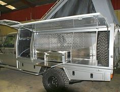 a silver truck parked inside of a garage next to a tent on top of it