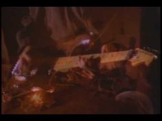 two people playing guitars in a dark room