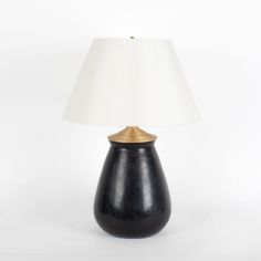 a black lamp with a white shade on it and a gold trim around the base