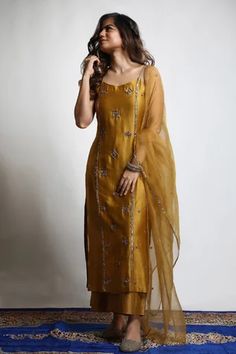 Burnt gold straight kurta in dupion silk base with zari and sequins hand embroidered tiered motifs. Comes with wide legged pant and an organza dupatta.
Component: 3
Pattern: Embroidered
Type Of Work: Zari, Sequins
Neckline: Round
Sleeve Type: Sleeveless
Fabric: Kurta and Pant : Dupion Silk, Dupatta : Organza 
Color: Gold
Other Details: 
Closure : Pant : Fixed belt at front and elastic at back, Opening on the side with a Zip and Hook
Occasion: Mehendi and Haldi, Sangeet - Aza Fashions Long Straight Kurti Designs, Lehanga Idea, Salwars Design, Girly Suit, Haldi Dresses, Silk Kurtis, Cotton Anarkali Kurta, Kurtis Design, Ethnic Dresses