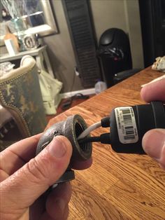 two hands are holding an electrical tool on a table