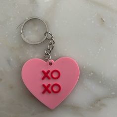 a pink heart shaped keychain with the word xo on it's side