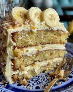 a blue and white plate topped with a piece of cake covered in banana slices next to a fork