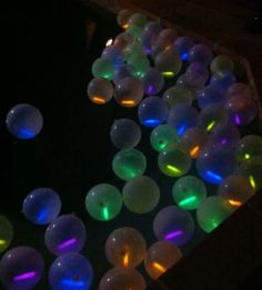 glow in the dark balls are floating on the ground and glowing up with colored lights