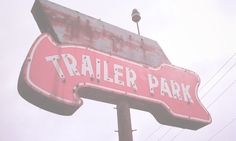 a pink trailer park sign on top of a metal pole