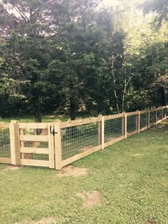 a fence that is made out of wood and wire with trees in the back ground