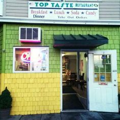 the front entrance to top taste restaurant, which is painted green and yellow with white trim