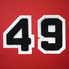 the number 94 is made out of black and white felt on a red background,