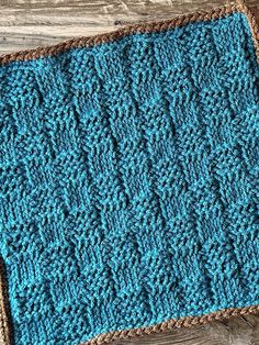 a crocheted blue and brown dishcloth sitting on top of a wooden table