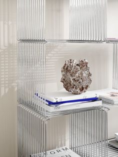 a book shelf filled with books on top of each other in front of a white wall