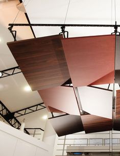 several wooden panels suspended from the ceiling in a room with white walls and lights above them