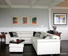 a living room with white furniture and pictures on the wall