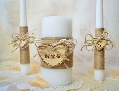 three white candles with burlocks and twine wrapped around them on a lace tablecloth