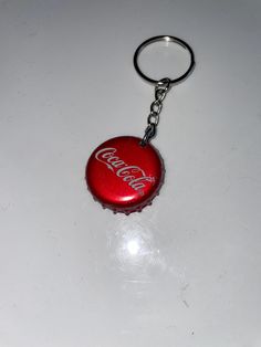 a red bottle cap keychain with the word coca - cola printed on it