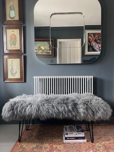 a bench in front of a mirror and pictures on the wall with a rug underneath it