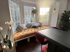 a room with a couch, table and some plants in the window sill next to it