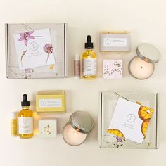 an assortment of skin care products displayed on a white surface next to candles and cards