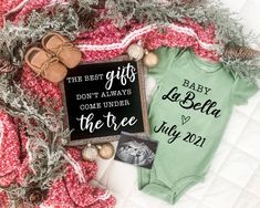 a baby onesuit and other items are laying on top of a blanket with christmas decorations