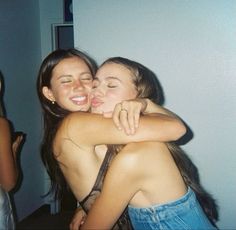 two young women hugging each other in a room