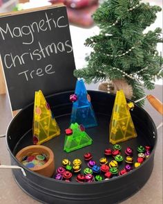 a christmas tree is in a tray with magnets on it and a sign that says magnetic christmas tree