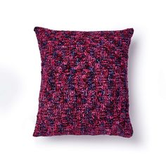 a red and purple pillow sitting on top of a white wall