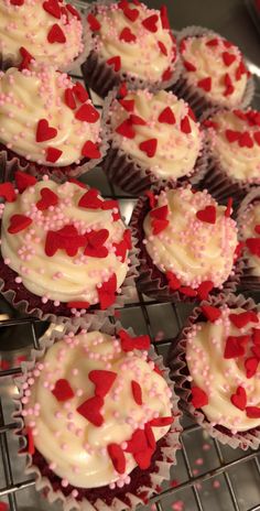 cupcakes with white frosting and red sprinkles on a cooling rack