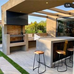 an outdoor kitchen with two stools next to it and a grill in the back