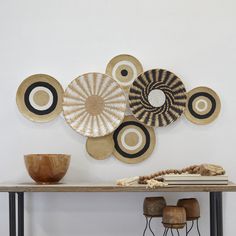 a table topped with bowls and plates on top of it next to a wall mounted art piece