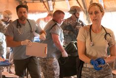 a group of people standing around each other with medical supplies on their hands and in scrubs